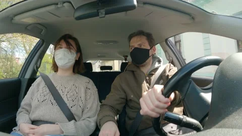 Interior dashcam - two people with face masks inside a car driving through town Stock Footage 238042480