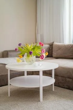 Interior design warm beige sofa and white round table with colourful flowers on Foto stock