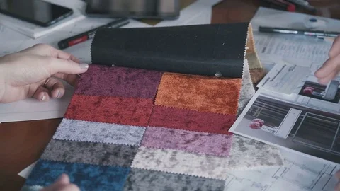 Interior designer in his studio shows fabric samples to woman client Stock Footage 75897105