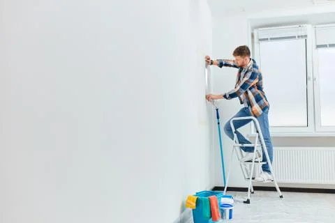 Interior designer measuring wall with flexible ruler in empty white appartment Stock Photos