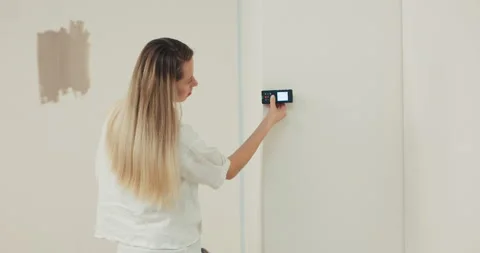 Interior designer walks around property for sale uses distance meter to measure Stock Footage 214026436