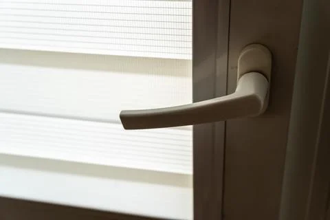 Interior door handle with textured window blind background, illustrating home Stock Photos