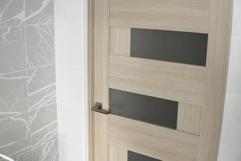 Interior doors on the kitchen side with white and gray tiles on the wall. Stock Photos