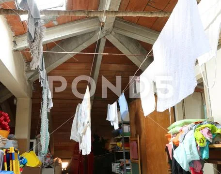 Interior of a dusty attic with hanged tatters and rags without people Stock Photos
