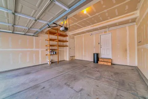 Interior of empty attached garage with white door that leads inside the house Stock Photos