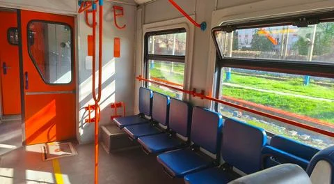 Interior of an empty city train carriage with blue seats and orange handrails Stock Photos