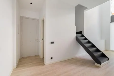 Interior of empty renovated apartment in a duplex flat with black stairs leading Photos