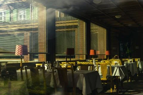 Interior of empty restaurant lit by the light from the blinds Stock Photos