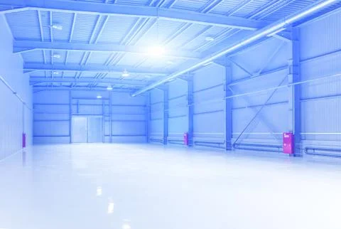 Interior of empty warehouse with blue light flare Stock Photos