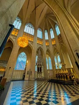 Interior of gothic cathedral featuring checkered floor and stained glass windows Stock Photos