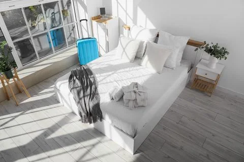 Interior of hotel room with bed, table and suitcase Stock Photos