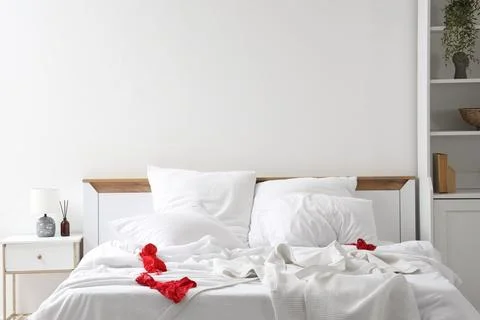 Interior of hotel room with bedside table, unmade bed, crumpled linen and fem Stock Photos