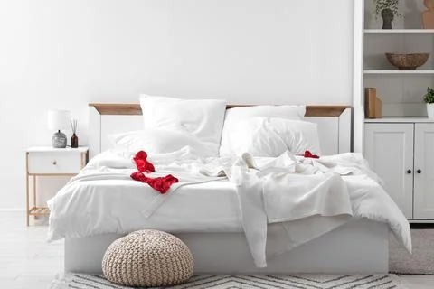 Interior of hotel room with bedside table, unmade bed, crumpled linen and fem Stock Photos