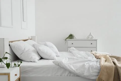 Interior of hotel room with commode, bedside table, unmade bed and crumpled l Stock Photos