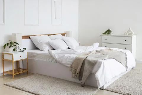 Interior of hotel room with commode, bedside table, unmade bed and crumpled l Stock Photos