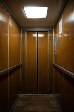 Interior inside a closed clean old Soviet elevator car lined with wood. Stock-Fotos