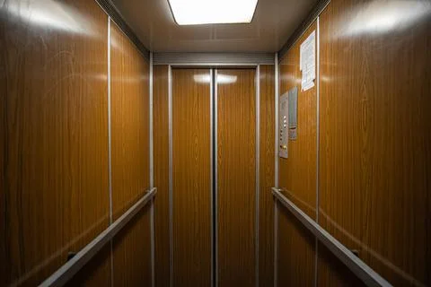 Interior inside a closed clean old Soviet elevator car lined with wood. Stock Photos