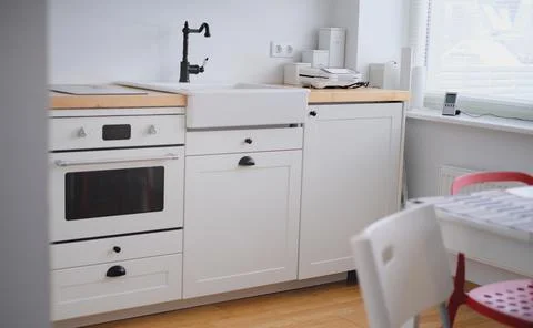 The interior of a kitchen in white tones with a sink, sandwich maker, stove Stock Photos