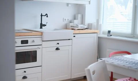 The interior of a kitchen in white tones with a sink, sandwich maker, stove Stock Photos