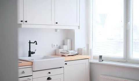 The interior of a kitchen in white tones with a sink, sandwich maker, stove Stock Photos