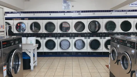 Interior of large self service laundry shop with ceiling fan. Rows and lines of Stock Footage 124124852
