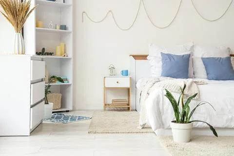 Interior of light bedroom with table, shelf unit and commode Stock Photos