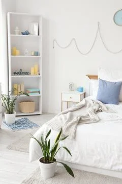 Interior of light bedroom with table, shelf unit and plants Stock Photos