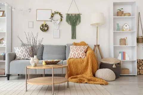 Interior of light living room with Easter wreaths, sofa and table Stock Photos