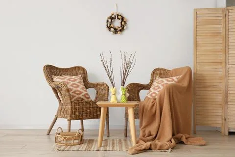Interior of light living room with Easter wreath, wicker armchairs and table Stock Photos