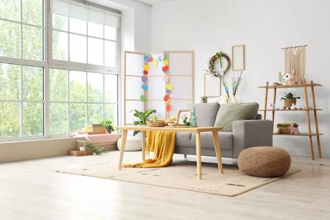 Interior of light living room with Easter wreath, sofa and table Stock Photos