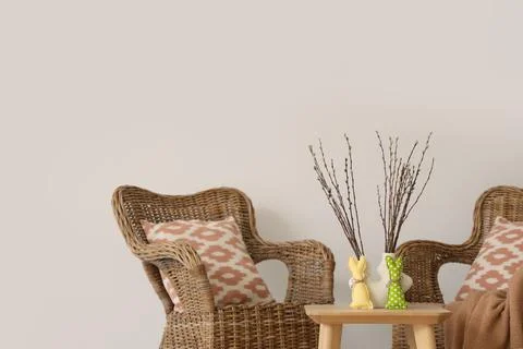 Interior of light living room with Easter wreath, wicker armchairs and table Stock Photos