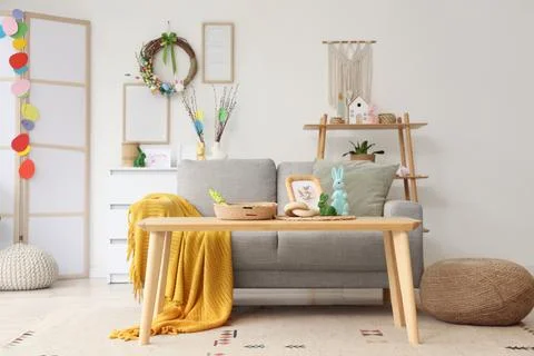 Interior of light living room with Easter wreath, sofa and table Stock Photos