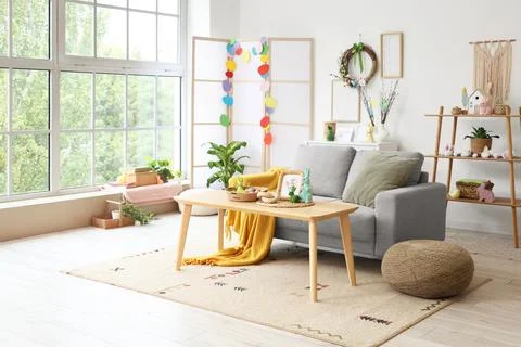 Interior of light living room with Easter wreath, sofa and table Stock Photos