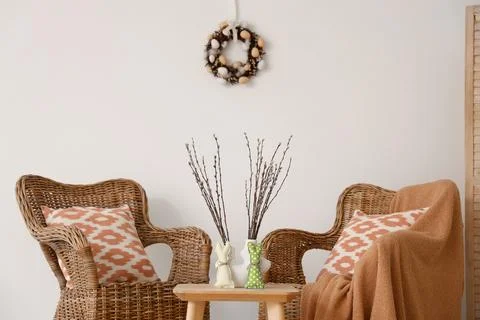 Interior of light living room with Easter wreath, wicker armchairs and table Stock Photos