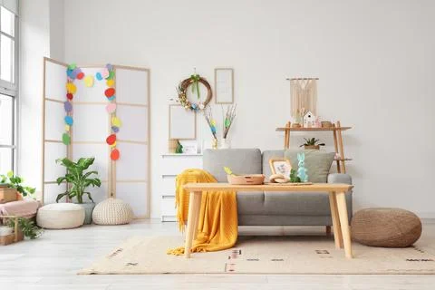 Interior of light living room with Easter wreath, sofa and table Stock Photos