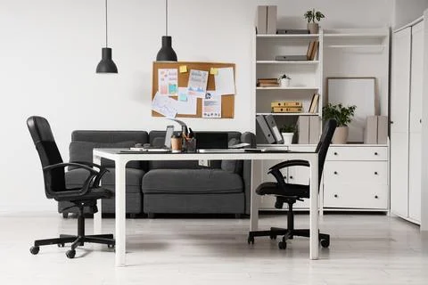 Interior of light office with printer on desk, sofa and shelf unit Stock Photos