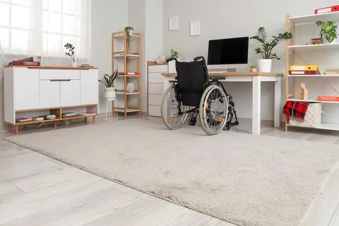 Interior of light office with shelf units, workplace and wheelchair Stock Photos