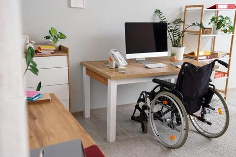 Interior of light office with workplace and wheelchair Stock Photos