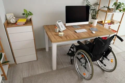 Interior of light office with workplace and wheelchair Stock Photos