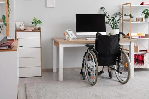 Interior of light office with workplace and wheelchair Stock Photos