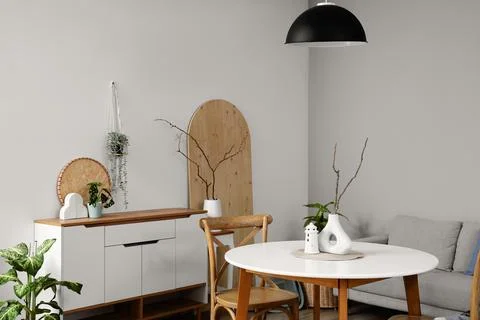 Interior of light room with dining table, sofa and commode Stock Photos