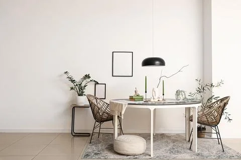 Interior of light room with dining table, frames and plants Фото