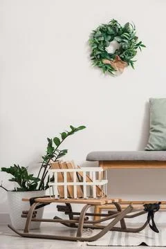Interior of light room with soft bench, Christmas wreath and sled Stock Photos