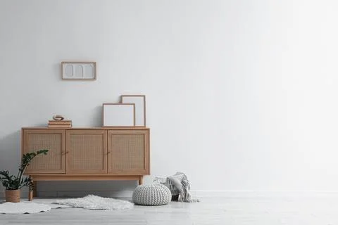 Interior of light room with wooden commode and blank frames Фото