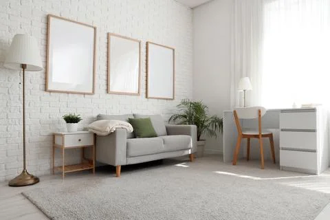 Interior of living room with blank frames, sofa and workplace Фото