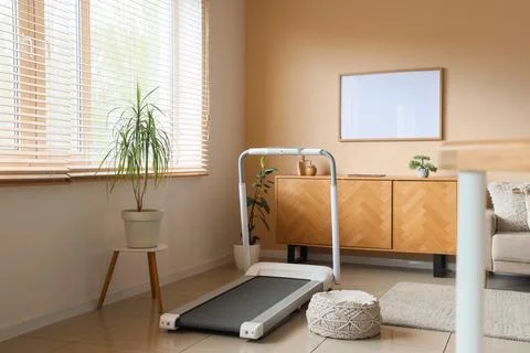 Interior of living room with treadmill, commode and plants Stock Photos
