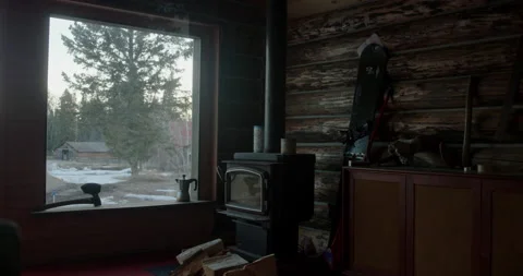 Interior log cabin next to cold fireplace with a window view to a snowy Stock Footage 156543934