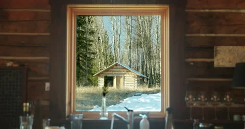 Interior log cabin window view of another small cabin at sunrise Stock Footage 156587529
