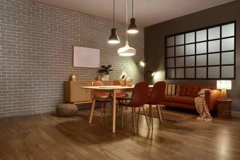 Interior of modern dining room with glowing lamps, sofa and table Stock Photos