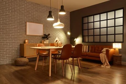 Interior of modern dining room with glowing lamps, sofa and table Stock Photos